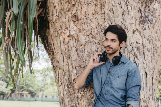 Relajante hombre con auriculares en el parque