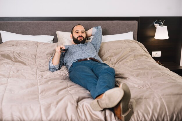 Relajante hombre viendo la televisión en el dormitorio