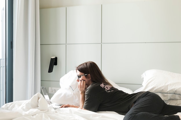 Relajante mujer viendo portátil en la cama