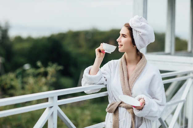 Relájate en las montañas. Chica joven y sonriente tiene un fin de semana y sosteniendo una taza con té, buenos días.