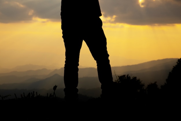 relaje al hombre en la colina en la silueta de la puesta del sol.