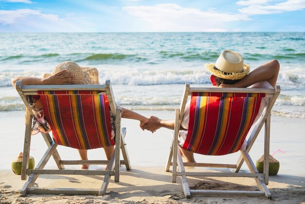 Relájese par acostarse en la playa chiar con ola de mar - hombre y mujer tienen vacaciones en el concepto de naturaleza de mar