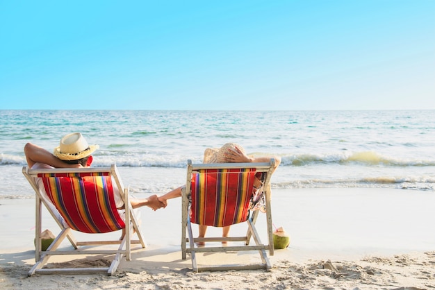 Relájese par acostarse en la playa chiar con ola de mar - hombre y mujer tienen vacaciones en el concepto de naturaleza de mar