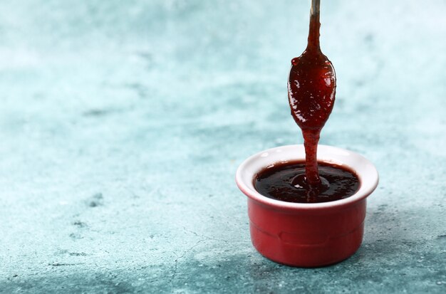 Relleno rojo confitura en una taza roja de una cuchara.