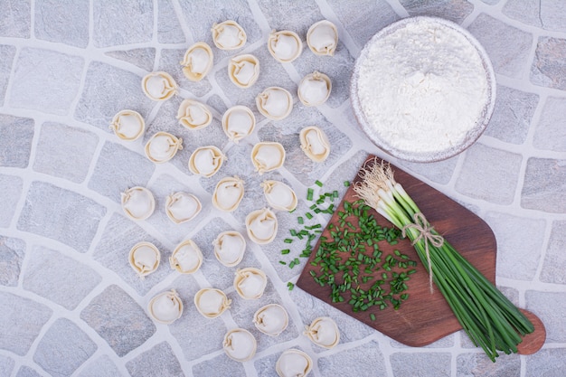 Foto gratuita rellenos khinkali en harina servidos con un manojo de cebolleta.