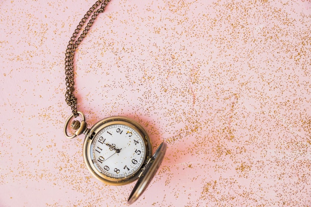 Reloj de bolsillo con lentejuelas en mesa.