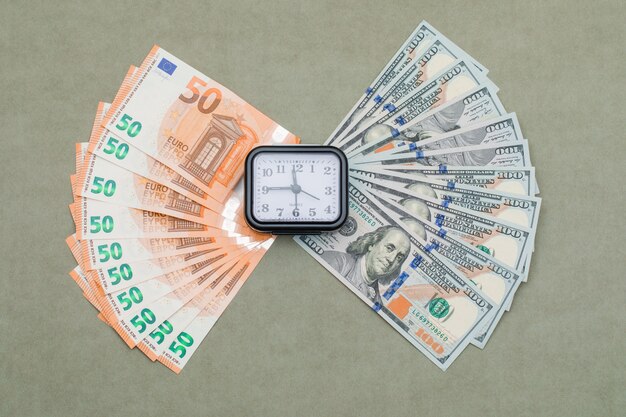 reloj, dólar y euro billetes en la mesa verde gris.