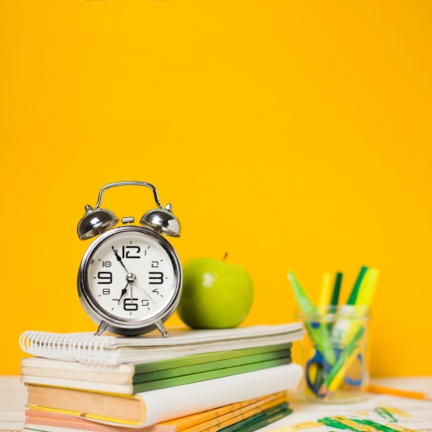 Reloj y libros con fondo desenfocado.