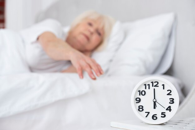 Foto gratuita reloj y mujer mayor dormida en el fondo
