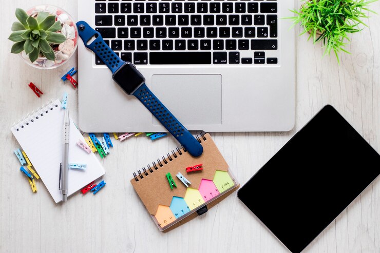 Foto gratuito reloj y papelería cerca de plantas y computadora portátil