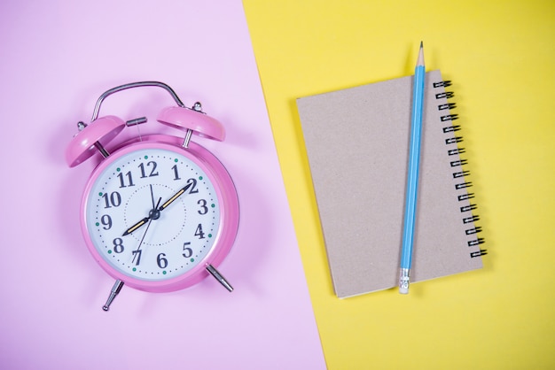 Reloj rosado en el fondo colorido, concepto de la educación