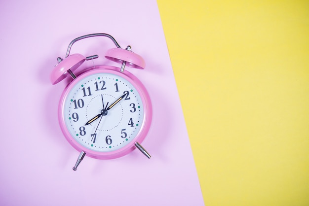 Reloj rosado en el fondo colorido, concepto de la educación