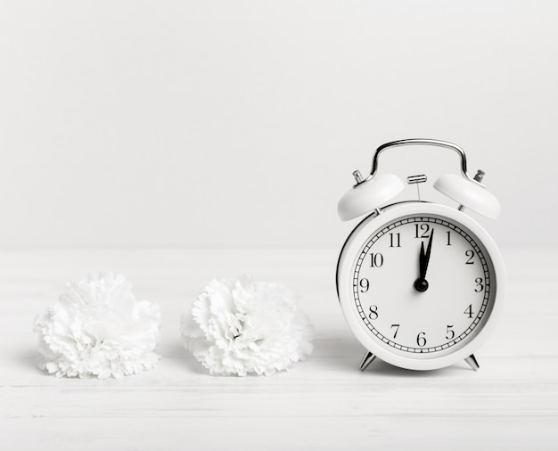 Reloj vintage con flores blancas al lado