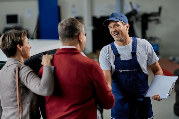 Reparador de automóviles feliz estrechando la mano con sus clientes en un taller