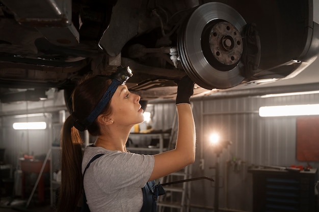 Reparador de automóviles femenino trabajando en la tienda en un automóvil