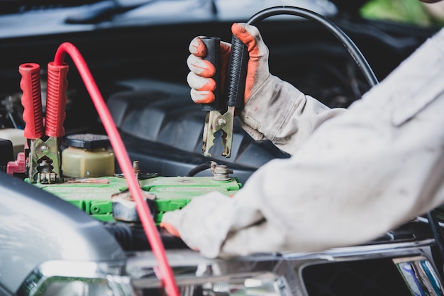 Reparador de automóviles con un uniforme blanco de pie y sosteniendo una llave que es una herramienta esencial para un mecánico