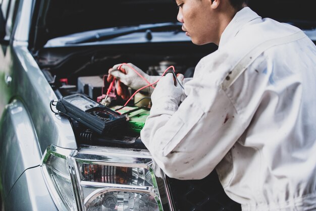 Reparador de automóviles con un uniforme blanco de pie y sosteniendo una llave que es una herramienta esencial para un mecánico
