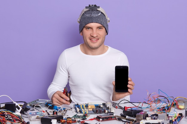 Reparador profesional reparando teléfonos inteligentes rotos, mostrando una pantalla en blanco con espacio de copia para publicidad