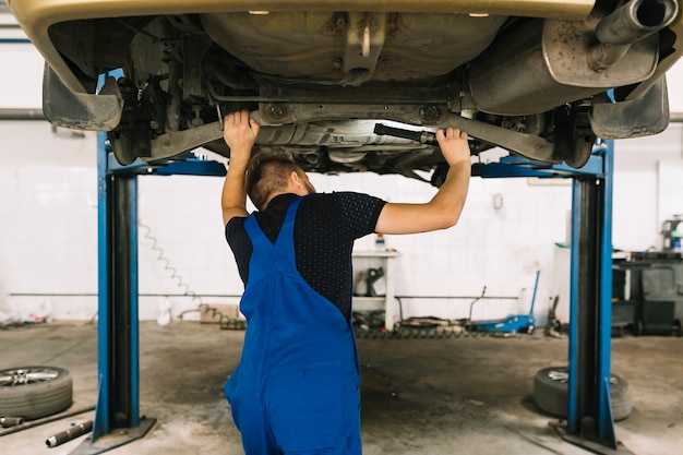 Reparadores que examinan el fondo del coche