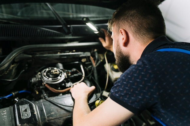 Reparadores que inspeccionan el motor del vehículo