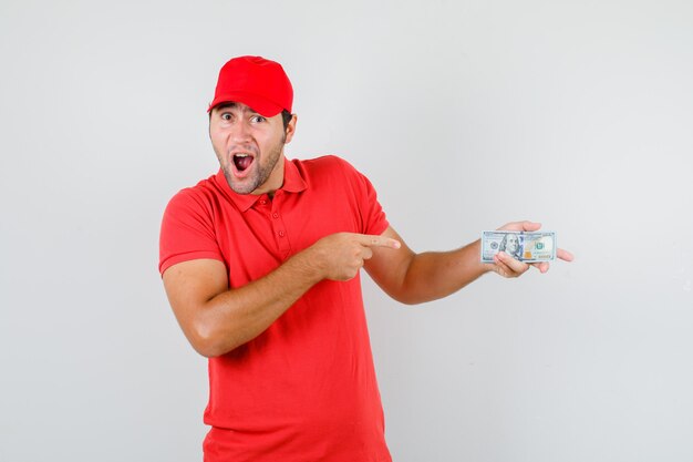 Repartidor apuntando al billete de dólar en camiseta roja