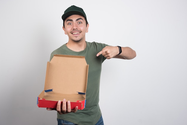 Repartidor apuntando a la caja de pizza vacía sobre fondo blanco.