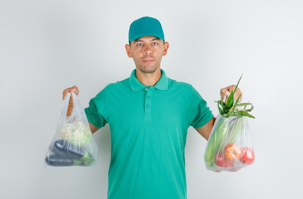 Repartidor con bolsas de polietileno con verduras en camiseta verde con gorra