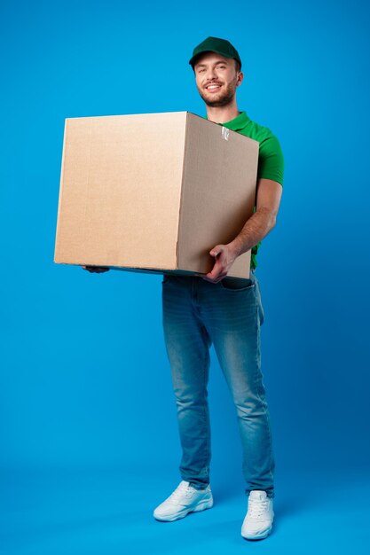 Repartidor con caja en estudio con fondo azul.