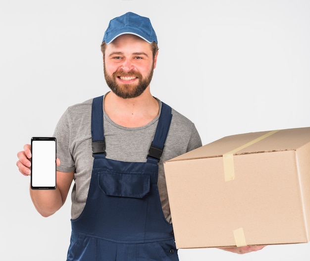 Foto gratuita repartidor con caja y teléfono inteligente con pantalla en blanco