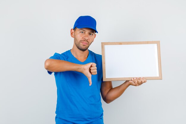 Repartidor en camiseta azul, gorra con pizarra blanca con el pulgar hacia abajo