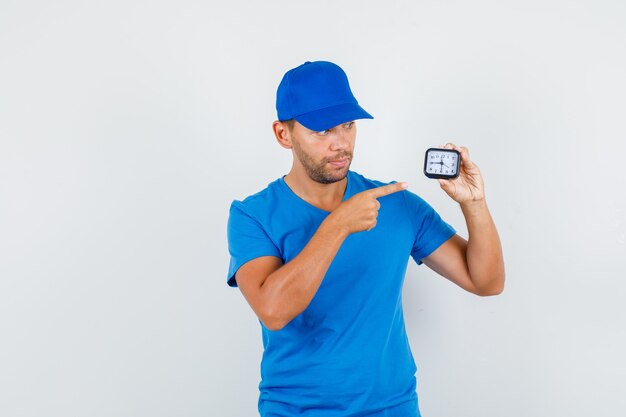 Repartidor en camiseta azul, gorra que señala el dedo en el reloj