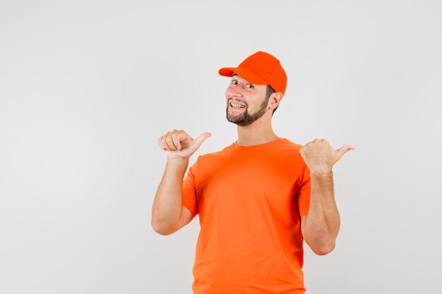 Repartidor en camiseta naranja, gorra apuntando con los pulgares dobles hacia un lado y mirando alegre, vista frontal.