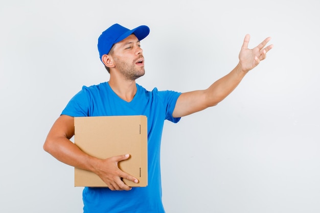 Repartidor dirigiéndose a alguien con caja de cartón en camiseta azul