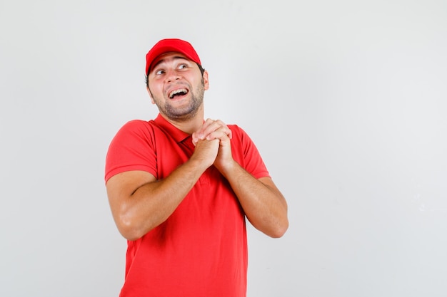 Repartidor estrechando las manos en gesto de oración en camiseta roja