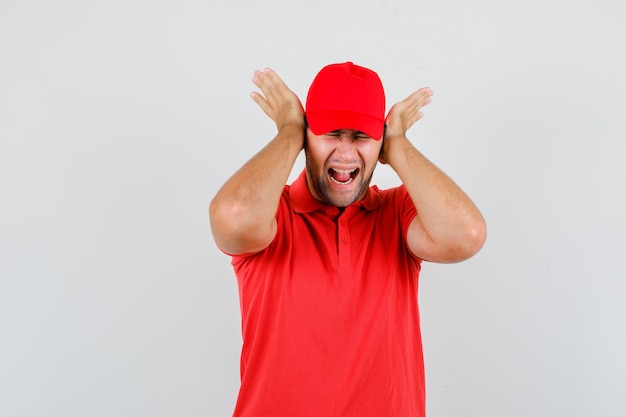 Repartidor gritando y tomados de las manos en los oídos en camiseta roja