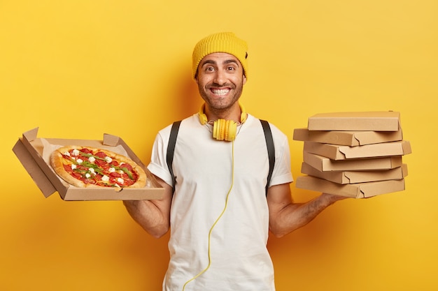 Repartidor guapo sonriente con cajas de pizza