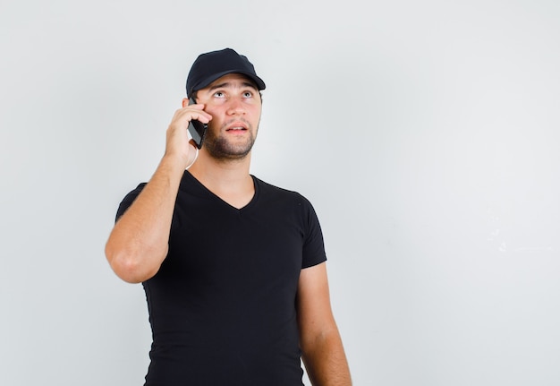 Repartidor hablando por teléfono inteligente en camiseta negra