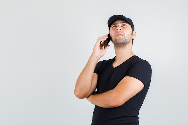 Repartidor hablando por teléfono inteligente en camiseta negra