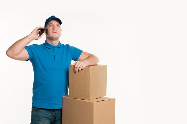 Repartidor hablando por teléfono y posando con cajas de cartón