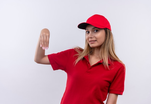 Repartidor joven complacido vistiendo uniforme rojo y gorra fingiendo sostener algo
