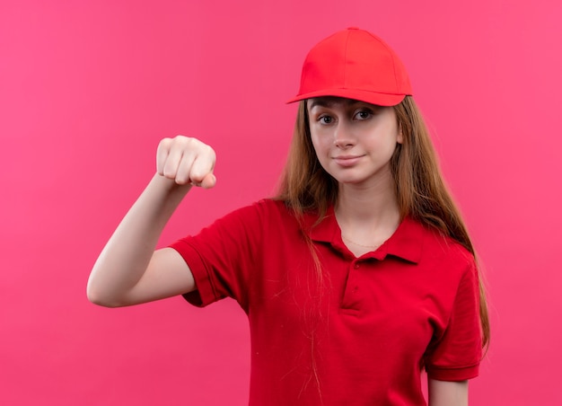 Repartidor joven confidente en uniforme rojo haciendo gesto de golpe en el espacio rosa aislado