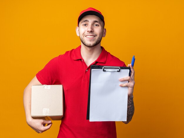 Repartidor joven sonriente vistiendo uniforme con caja de sujeción de tapa con portapapeles