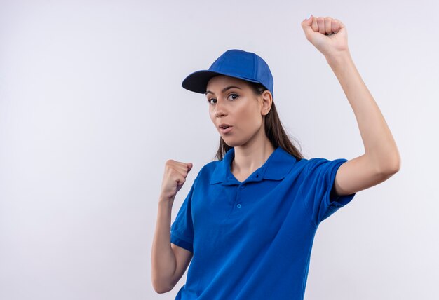 Repartidor joven en uniforme azul y gorra feliz y salido apretando los puños