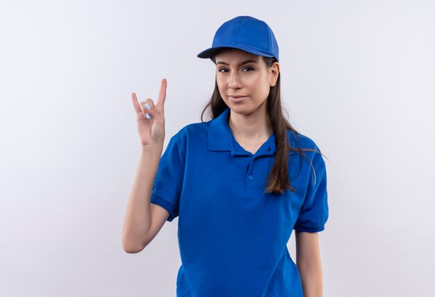 Repartidor joven en uniforme azul y gorra mirando confiado mostrando el símbolo de la roca con los dedos