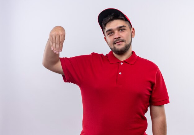 Repartidor joven en uniforme rojo y gorra mirando confiado gesticulando con las manos, concepto de lenguaje corporal