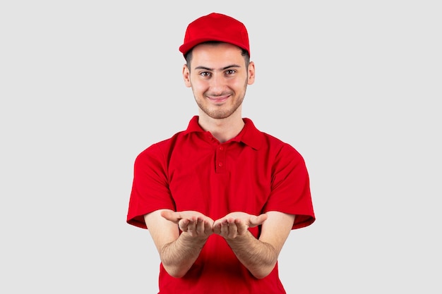 Foto gratuita repartidor joven en uniforme rojo de pie y posando