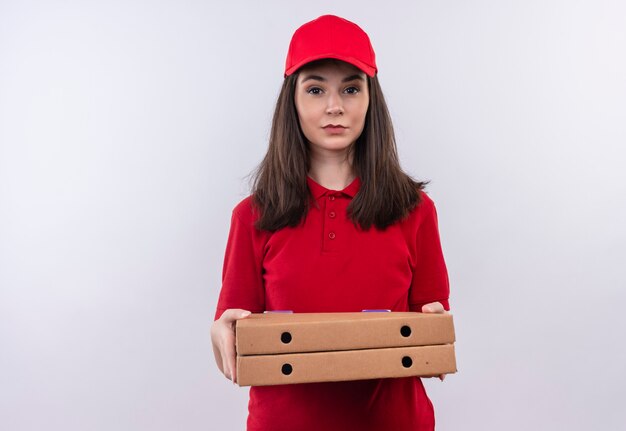 Repartidor joven vistiendo camiseta roja en gorra roja sosteniendo una caja de pizza sobre fondo blanco aislado