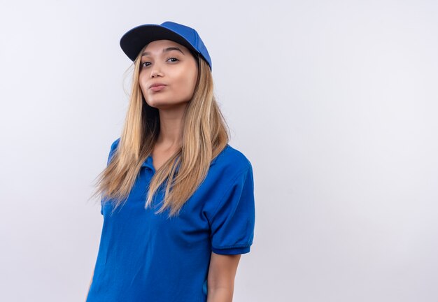 Repartidor joven vistiendo uniforme azul y gorra aislado en la pared blanca con espacio de copia