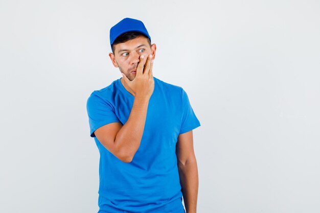 Repartidor con la mano en la cara en camiseta azul