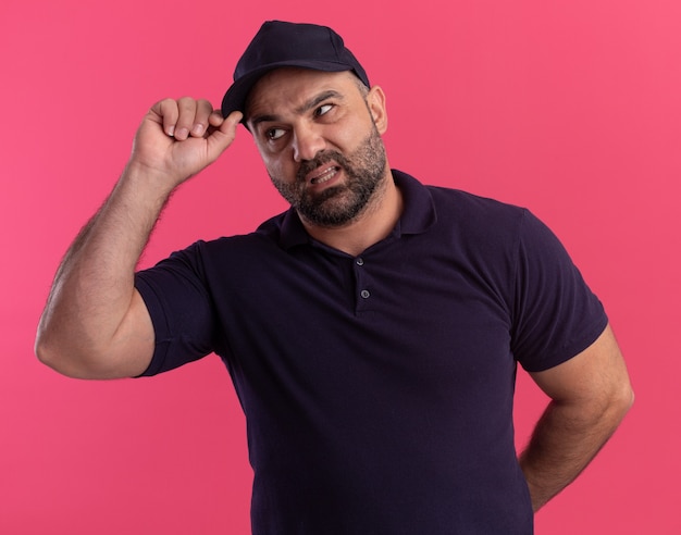 Foto gratuita repartidor de mediana edad disgustado en uniforme y gorra con gorra aislada en la pared rosa